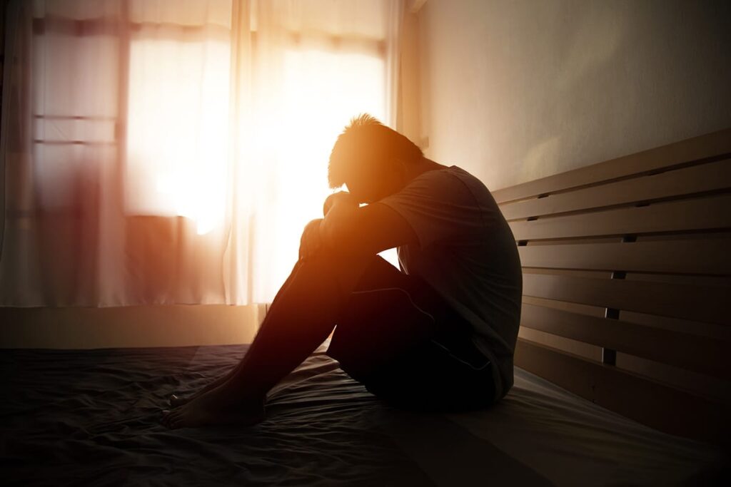 a person in a hallway sits on the floor struggling with signs of codeine addiction