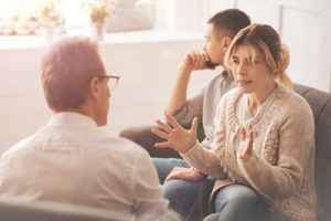 couple talks with a male therapist in family therapy program