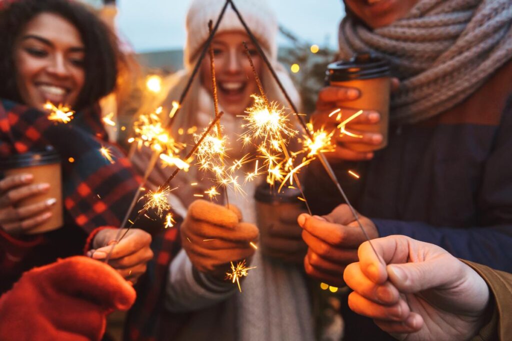 people hold sparklers in the cold, spending time with friends is one of many tips for a sober holidays