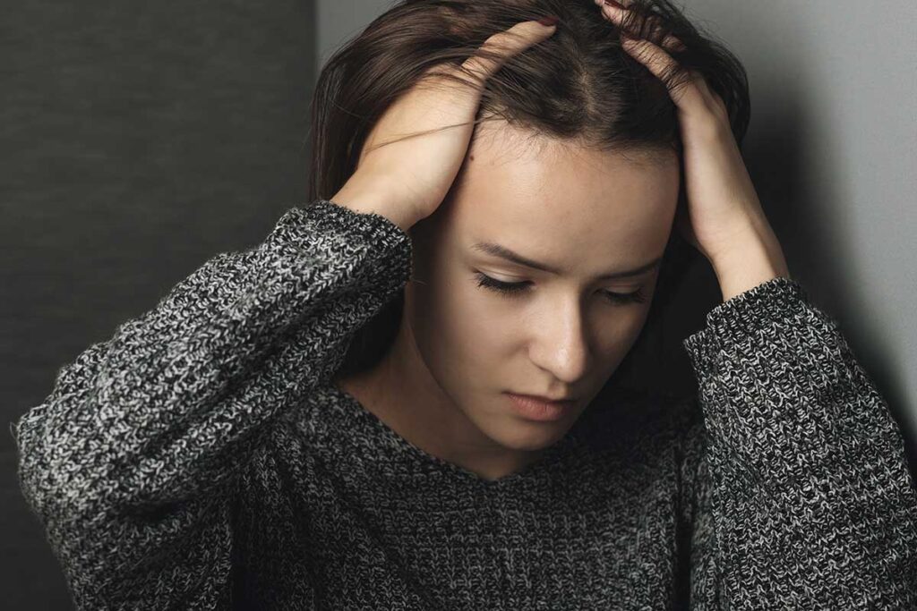 a person sits in a corner holding their head potentially going through an anxiety attack