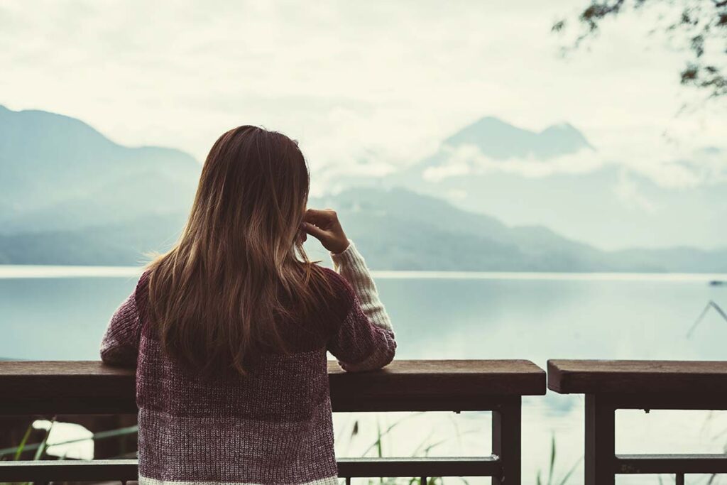 a person looks out on a lake thinkning about addiction mental health and your brain