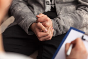 a person clasps their hands while talking to a therapist in an intensive outpatient program