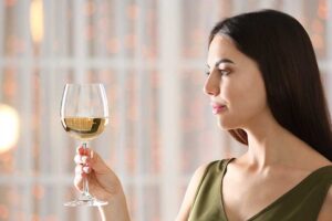 a woman looks at a glass of wine while in a fancy dress pondering an alcohol detox center
