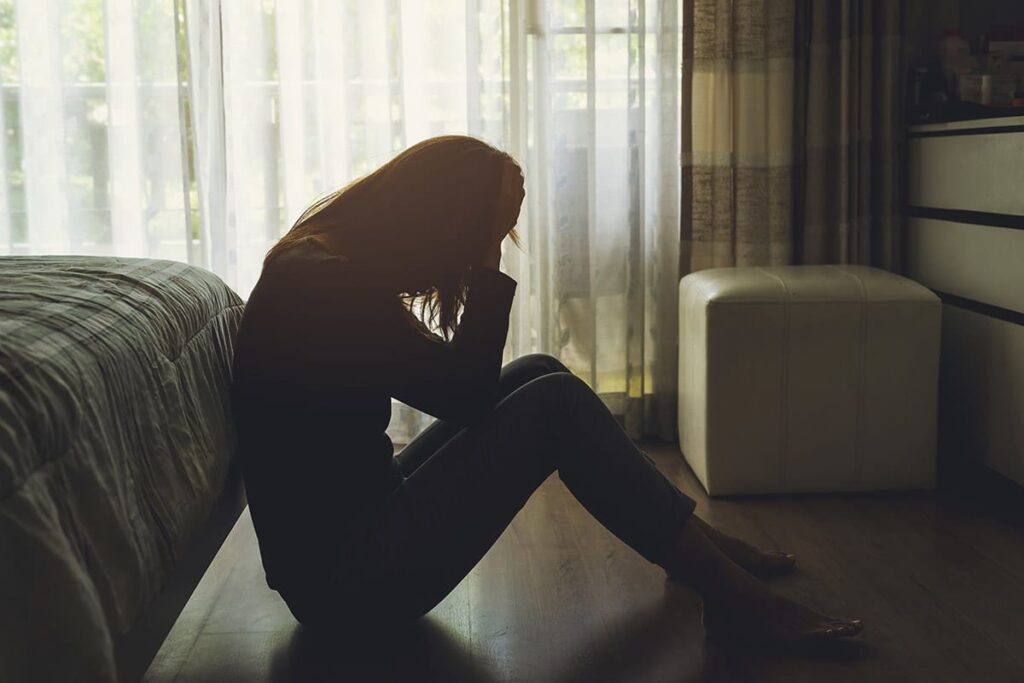 a person sits on the floor displaying the signs of a mental health crisis