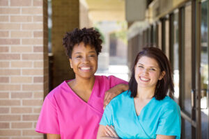 two nurses smile outside of a building at a partial hospitalization program