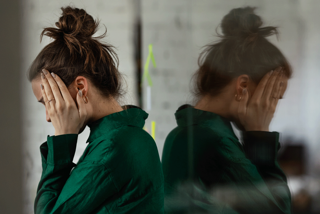 woman leans against a mirror holds the sides of her head with hands and asks herself is gabapentin addictive