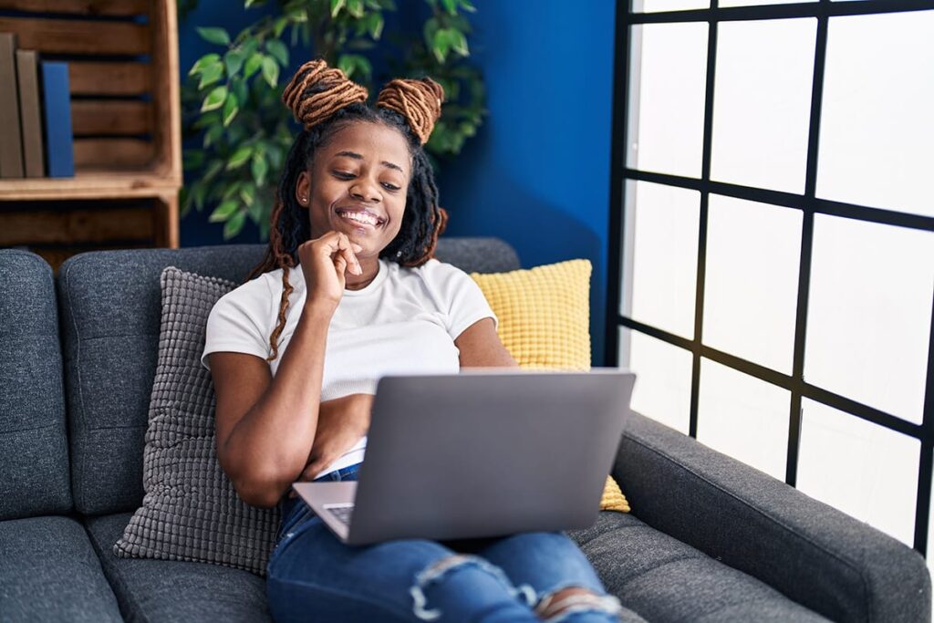 woman lays on her couch with a laptop on her lap with her hand to her chin thinking about what are dabs