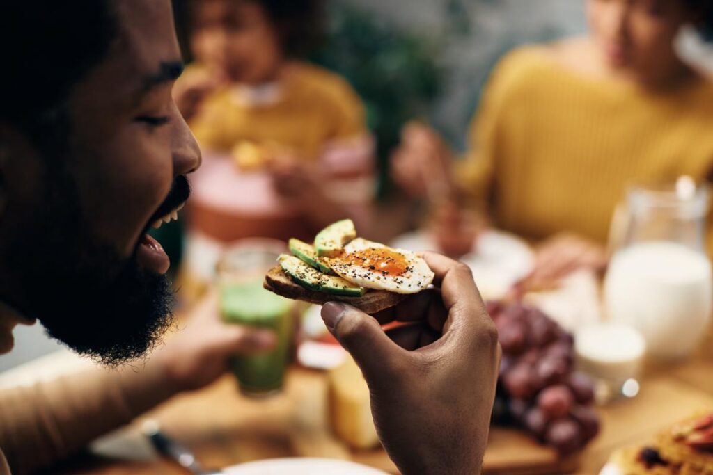 person eating avocado toast with egg after learning answers to does marijuana make you hungry