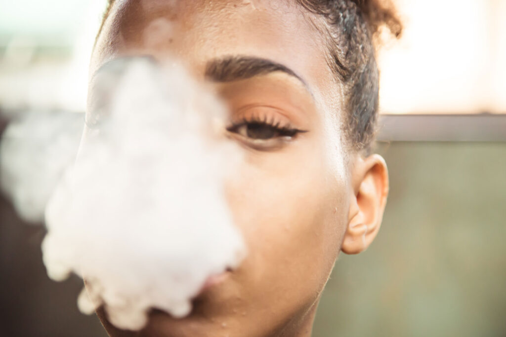 A girl is looking at the camera while smoking marijuana and experiencing paranoia.