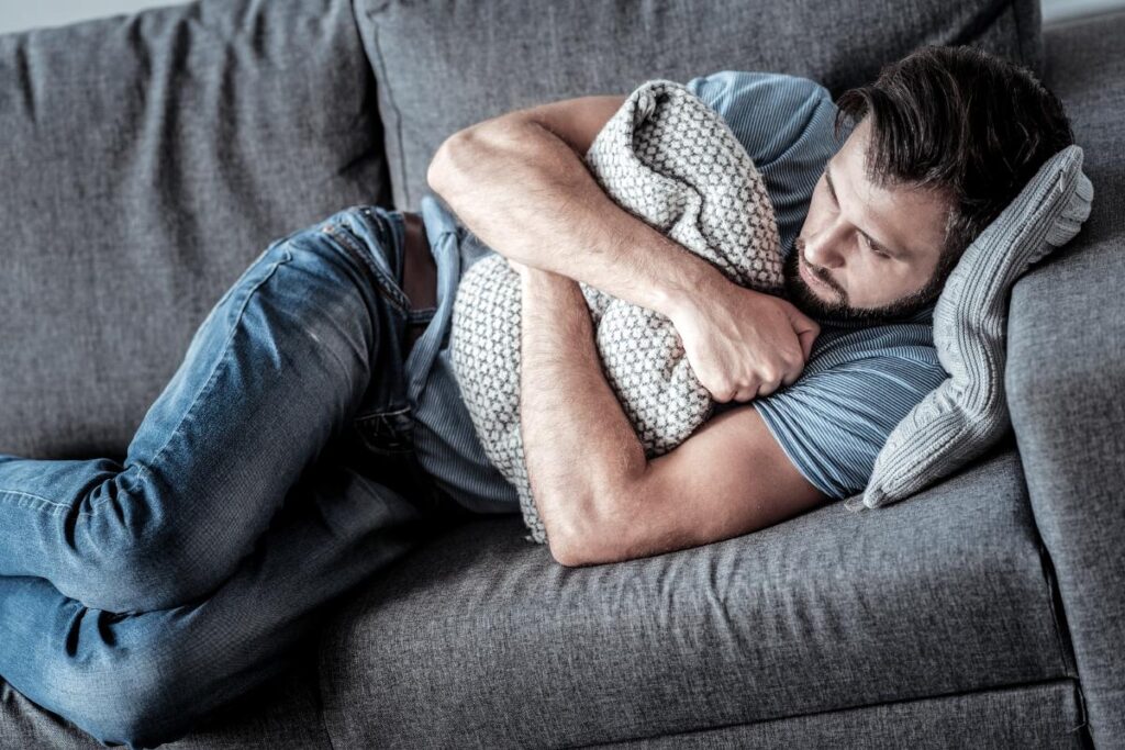 person lying on couch hugging pillow wondering does marijuana make you paranoid