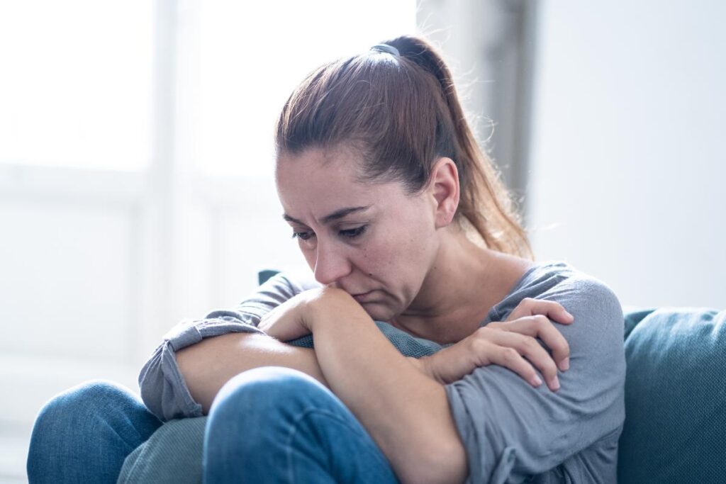 person sitting on couch looking distressed while wondering how long does fentanyl stay in your system