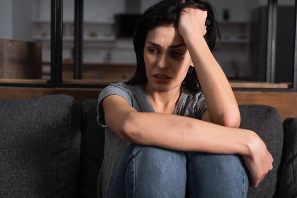 person sitting with knees pulled into chest while struggling with trauma and substance abuse