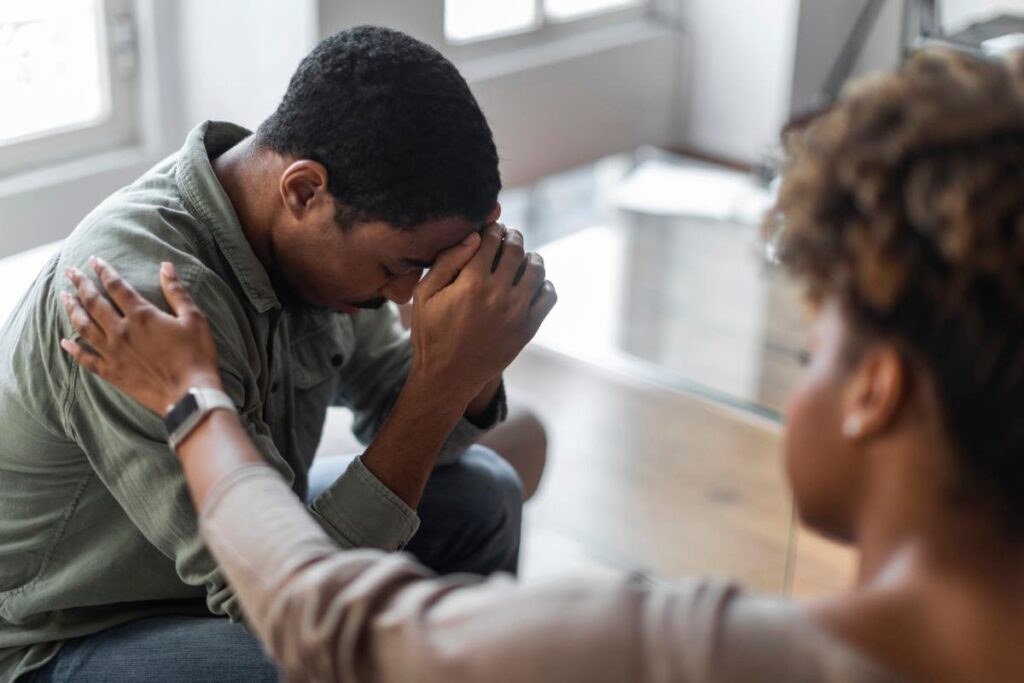 person hanging head in hands being comforted by therapist while finding answers to what is cannabis hypermesis syndrome