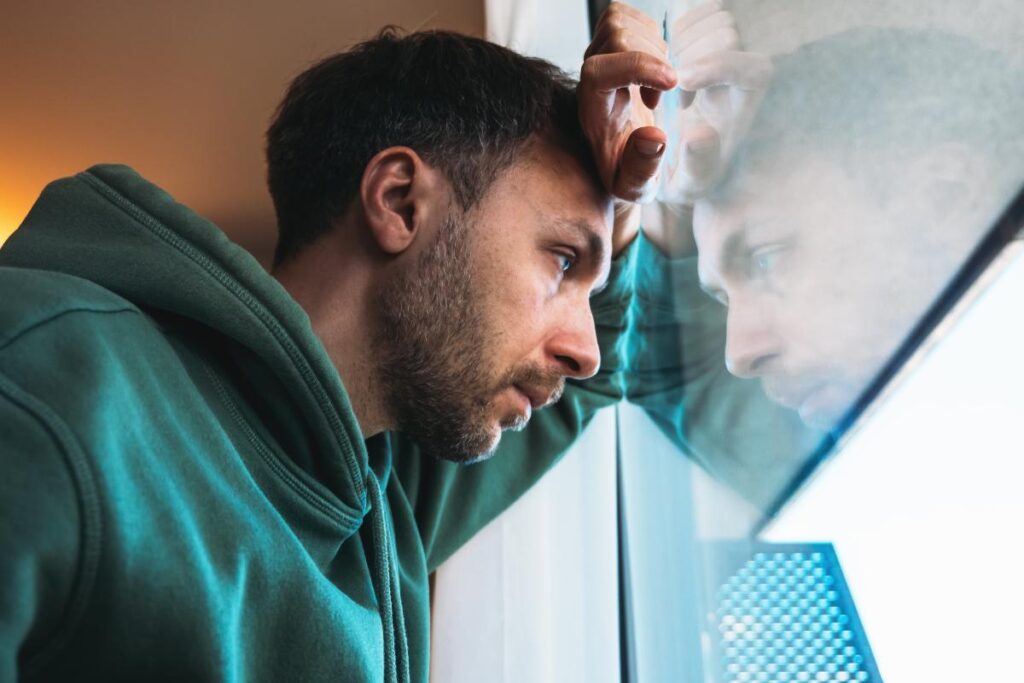 person leaning against window with contemplative look wondering is meth a stimulant