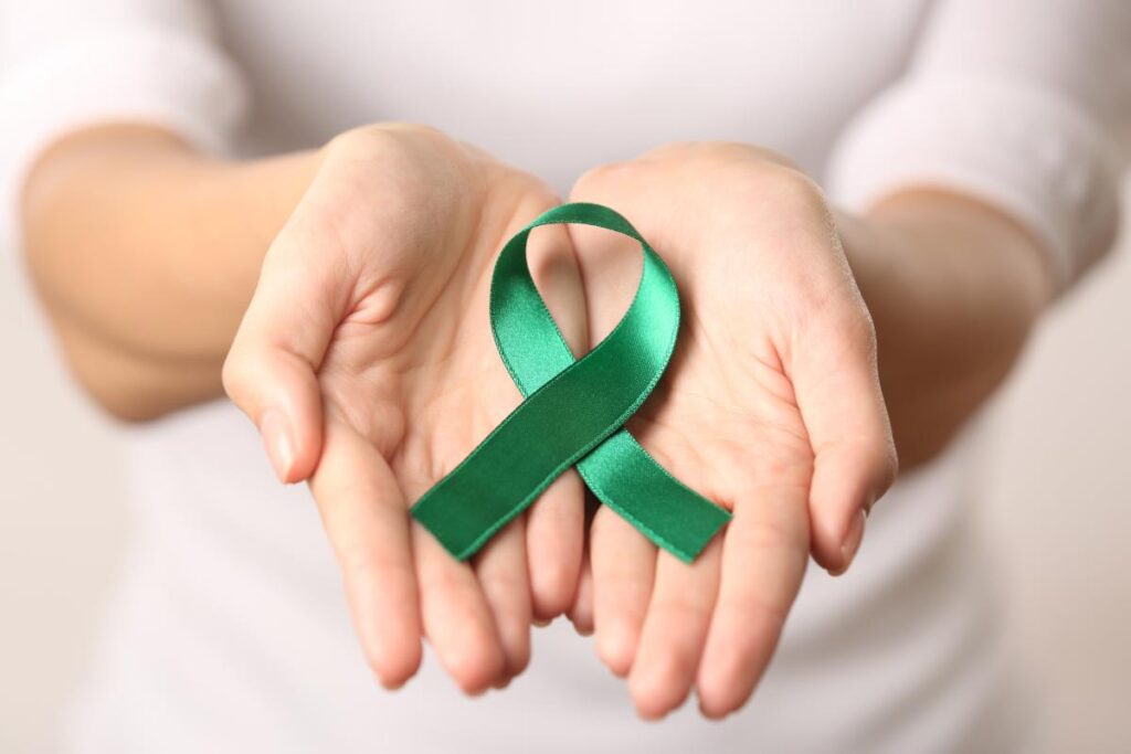 person holding green ribbon to symbolize mental health awareness month