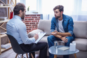 young man in an office setting discussing trauma therapy with a behavioral health professional