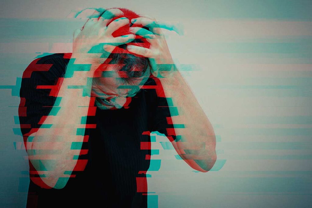 A man with both hands to his head is experiencing meth psychosis.
